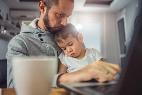 Dad doing homework with baby in lap